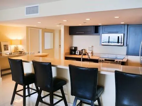 a kitchen with stainless steel appliances kitchen island granite countertop a sink a stove a dining table and chairs