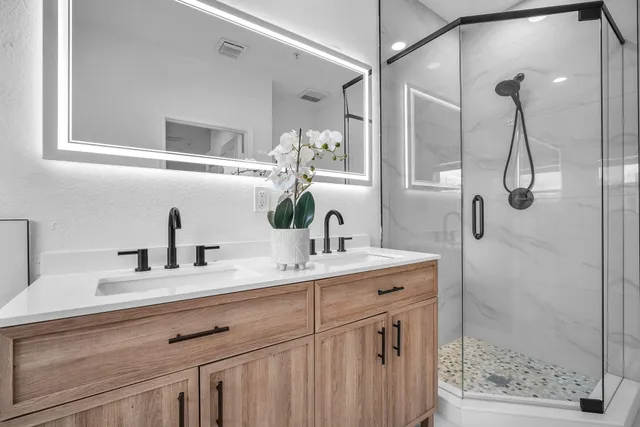 a bathroom with a granite countertop sink a mirror and shower