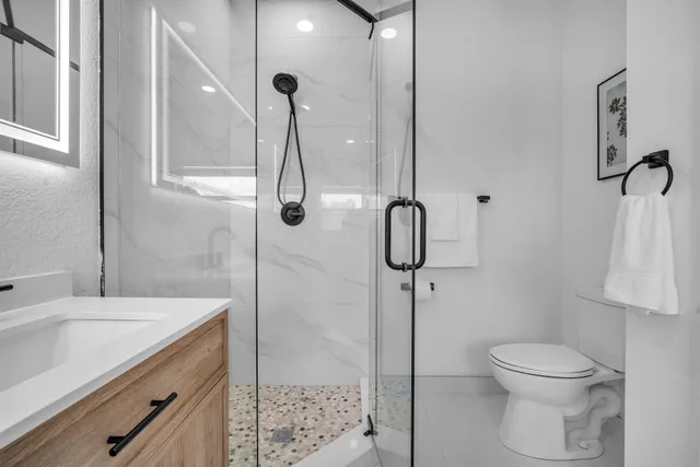a bathroom with a granite countertop sink toilet and shower