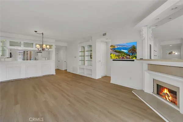 a view of empty room with wooden floor and kitchen view