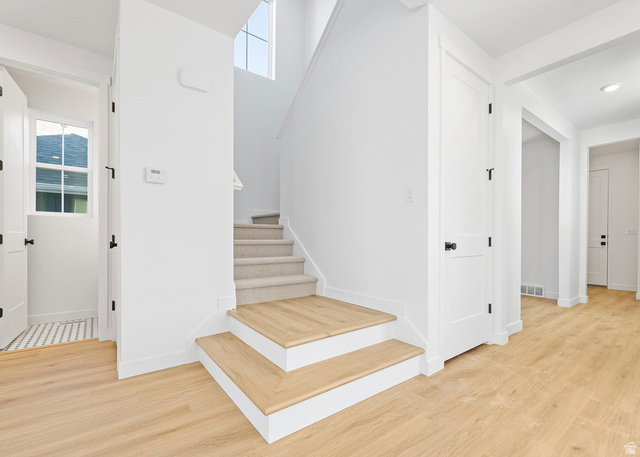 11214 South Easy Bee Road, Unit 270 South Jordan, UT 84009 - Photo 17 of 31 Entryway featuring light wood-finish flooring, white walls, and a staircase with carpeted treads