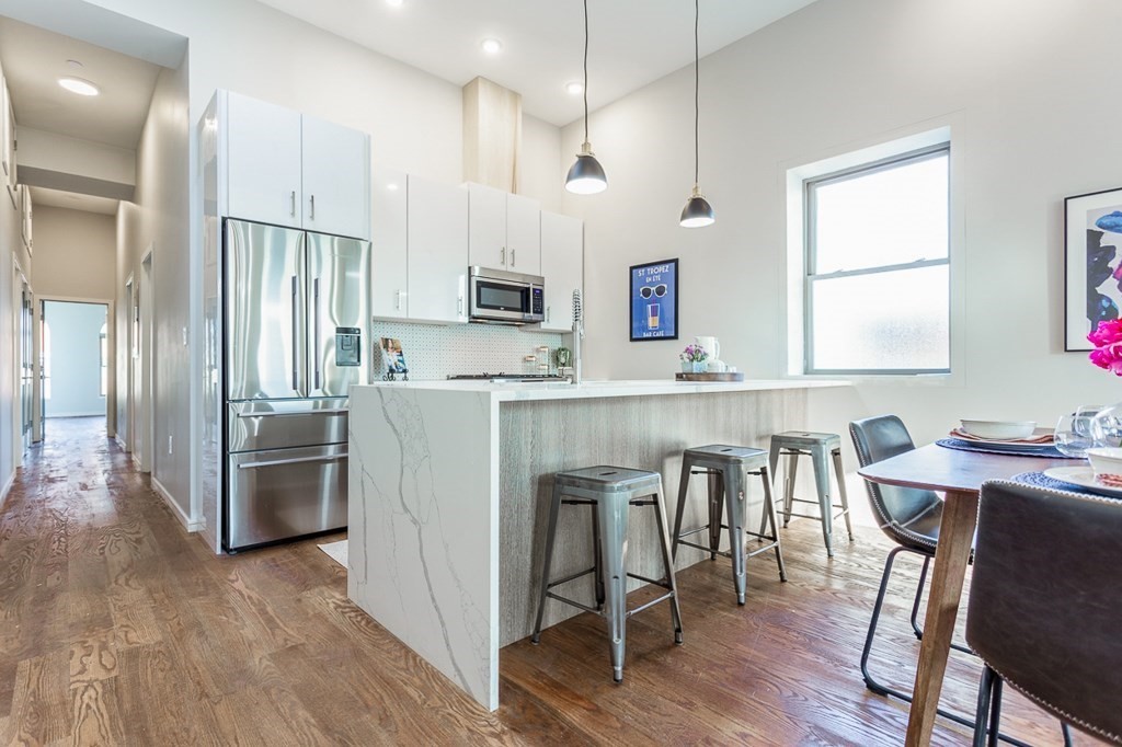 178 Elm Street, Unit 5 Cambridge, MA 02139 - Photo 3 of 14 a kitchen with kitchen island wooden floors white appliances and cabinets