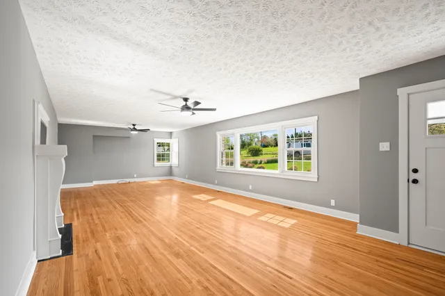 a view of an empty room with a window and wooden floor