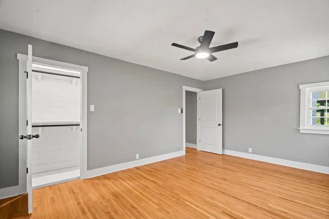 a view of a room with wooden floor ceiling fan and windows