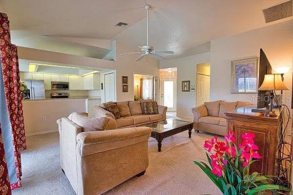 a living room with furniture kitchen view and a chandelier
