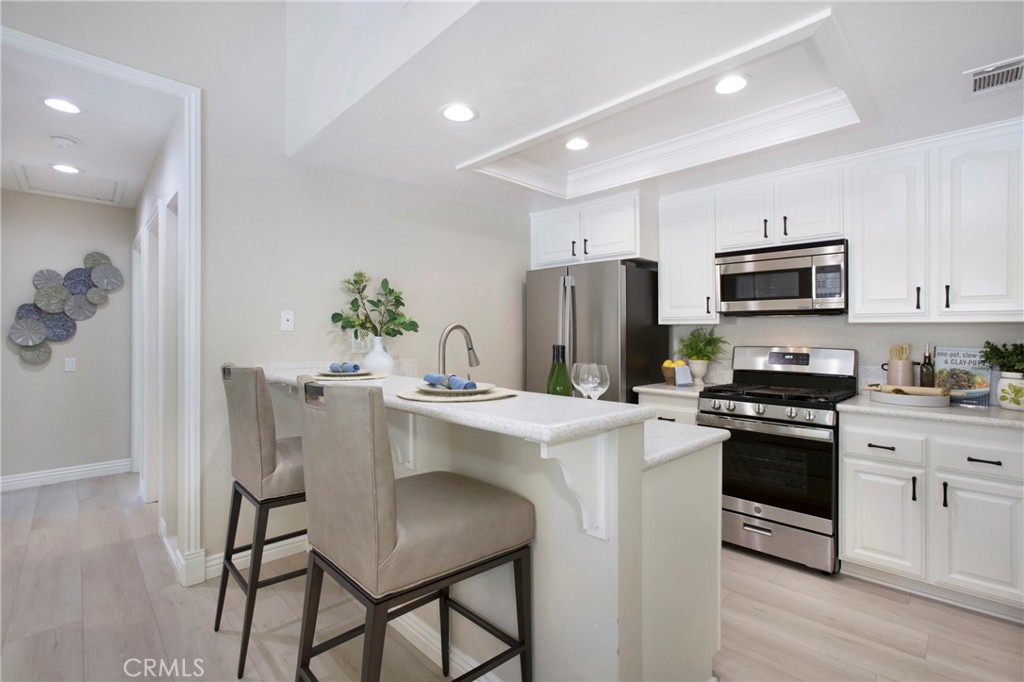 19 Spinnaker Irvine, CA 92614 - Photo 12 of 63 a kitchen with a sink a stove a refrigerator and a dining table with wooden floor
