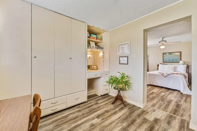 a hallway with a potted plant on the dresser and a wooden floor
