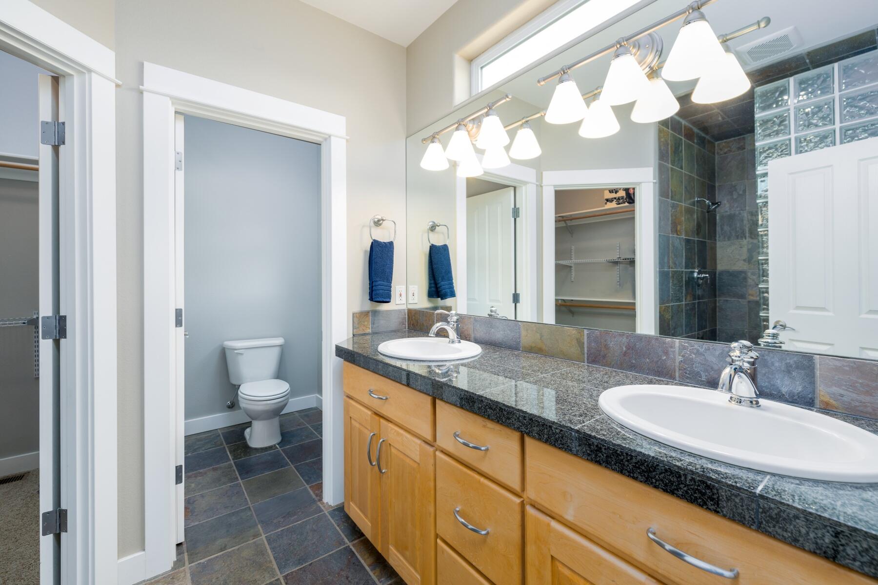 62732 Larkview Road Bend, OR 97701 - Photo 16 of 26 a bathroom with a granite countertop sink a toilet and a mirror