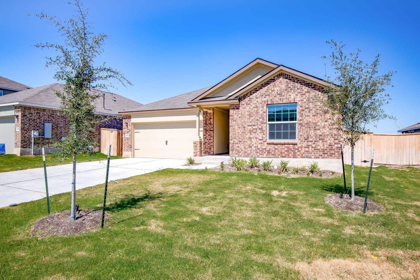 614 Milliner Loop Hutto, TX 78634 - Photo 2 of 25 A well-kept front yard and brick exterior create a welcoming curb appeal for this single-story home.
