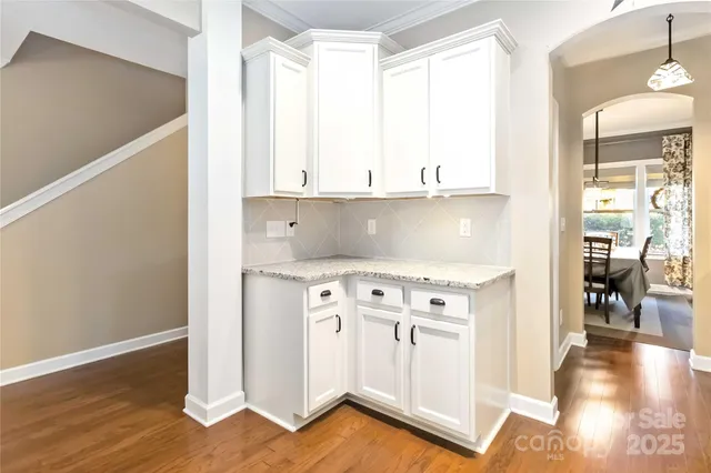 a kitchen with stainless steel appliances granite countertop a stove a sink and white cabinets with wooden floor next to windows