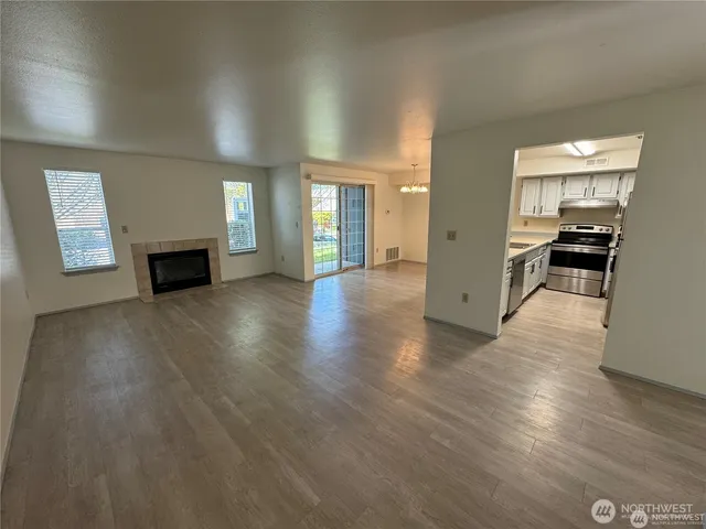 an empty room with windows fireplace and wooden floor