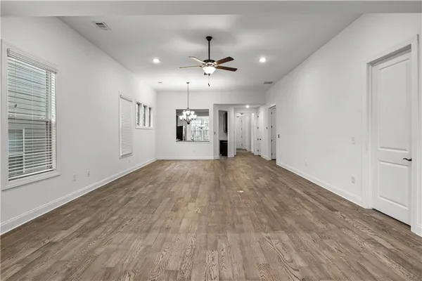 an empty room with wooden floor ceiling fan and windows