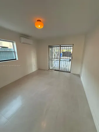 an empty room with chandelier fan and windows