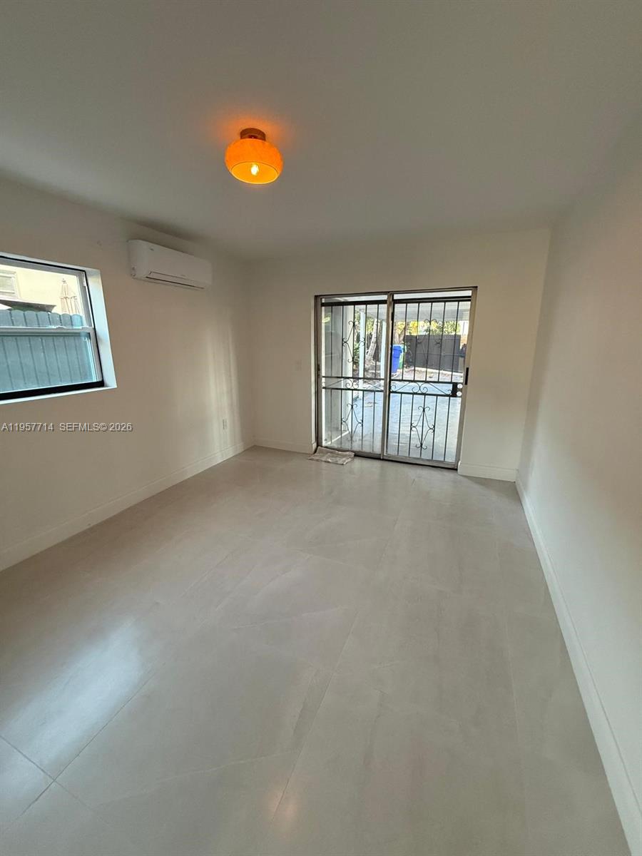 525 Southwest 22nd Avenue, Unit B Miami, FL 33135 - Photo 9 of 13 an empty room with chandelier fan and windows