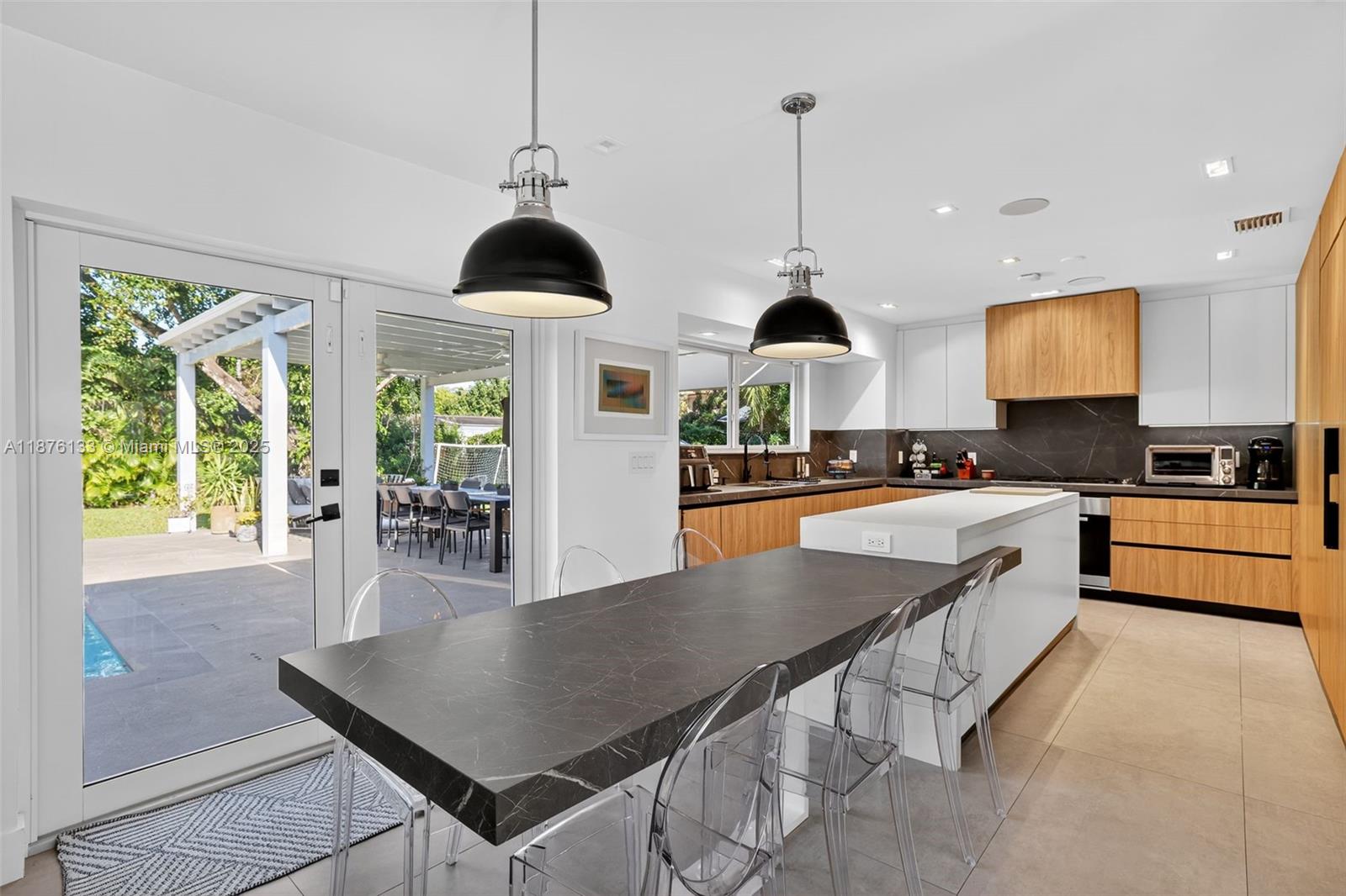 10740 Southwest 73rd Court Pinecrest, FL 33156 - Photo 6 of 37 a kitchen with stainless steel appliances granite countertop a stove a sink a microwave a dining table and chairs