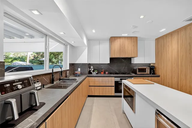 a kitchen with stainless steel appliances granite countertop a stove a sink and a refrigerator