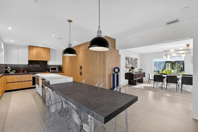 a kitchen with stainless steel appliances granite countertop a stove a sink a dining table and chairs with wooden floor