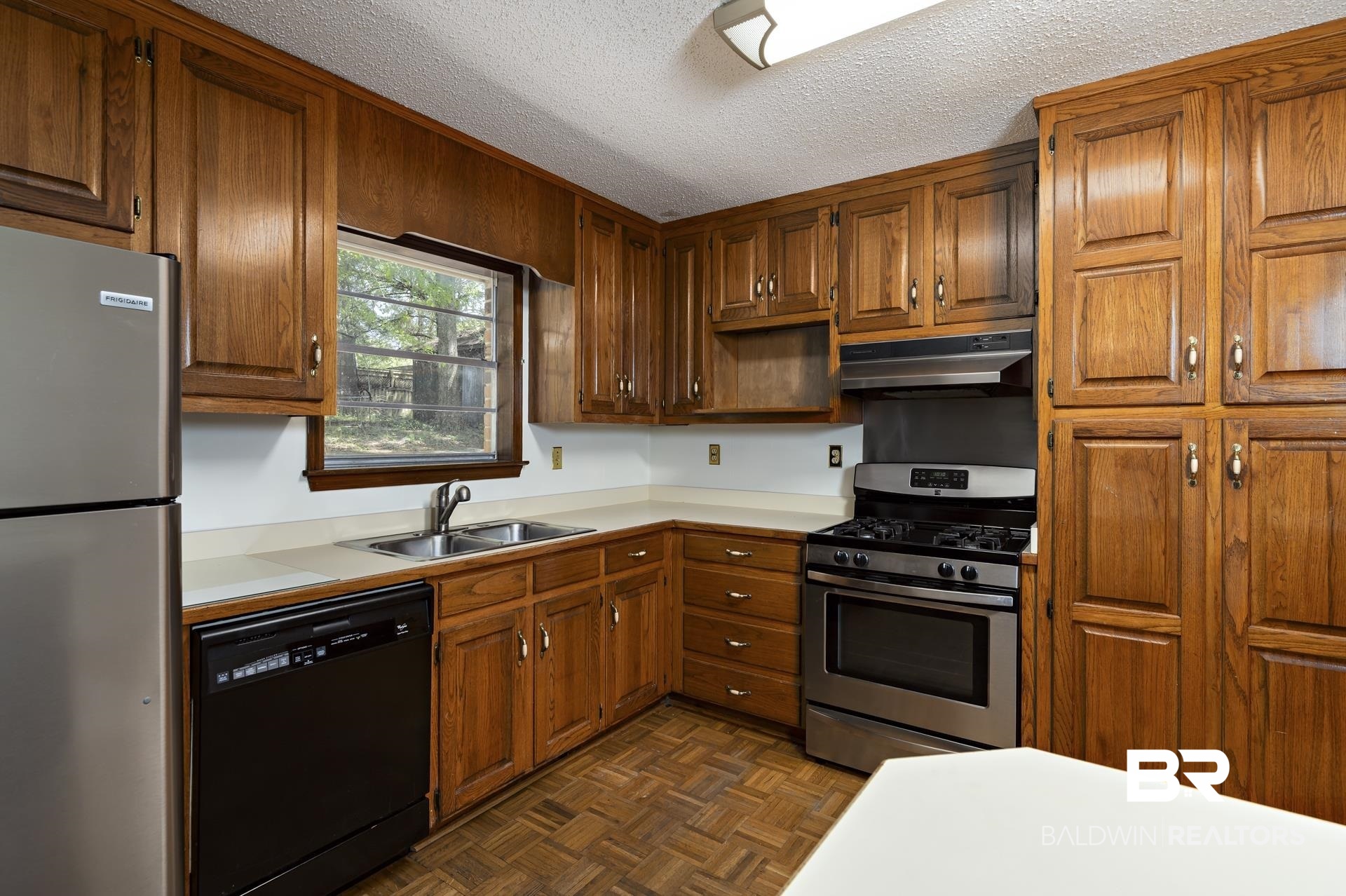 707 Johnson Avenue Fairhope, AL 36532 - Photo 19 of 38 Kitchen featuring under cabinet range hood, light countertops, a sink, and appliances with stainless steel finishes