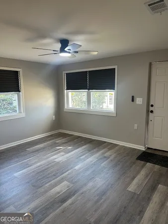 an empty room with wooden floor and windows