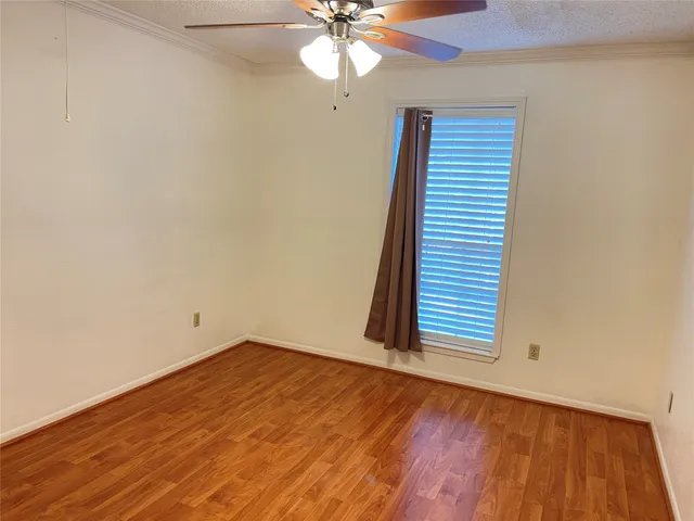 an empty room with wooden floor and fan