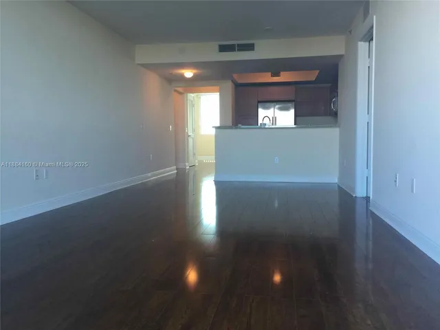a view of a hallway with wooden floor and a kitchen