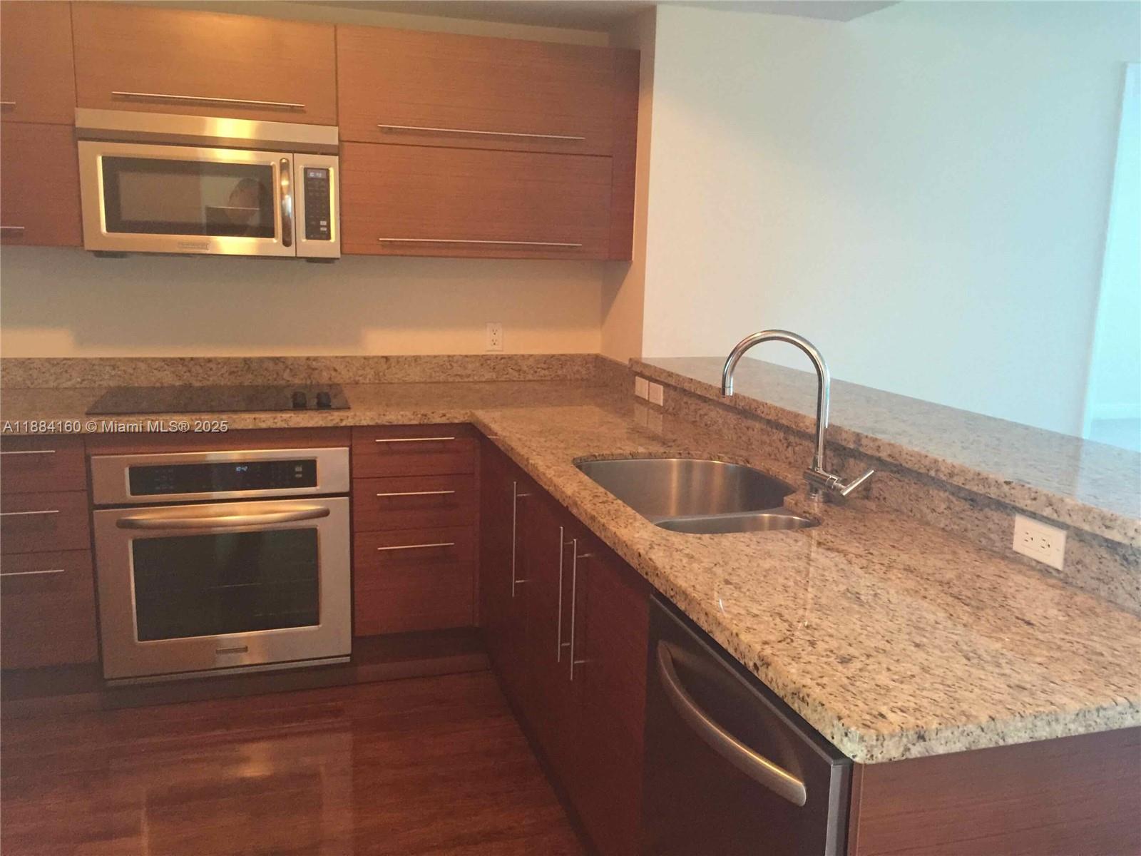 2641 North Flamingo Road, Unit 1705N Sunrise, FL 33323 - Photo 4 of 56 a kitchen with granite countertop a sink stove and microwave