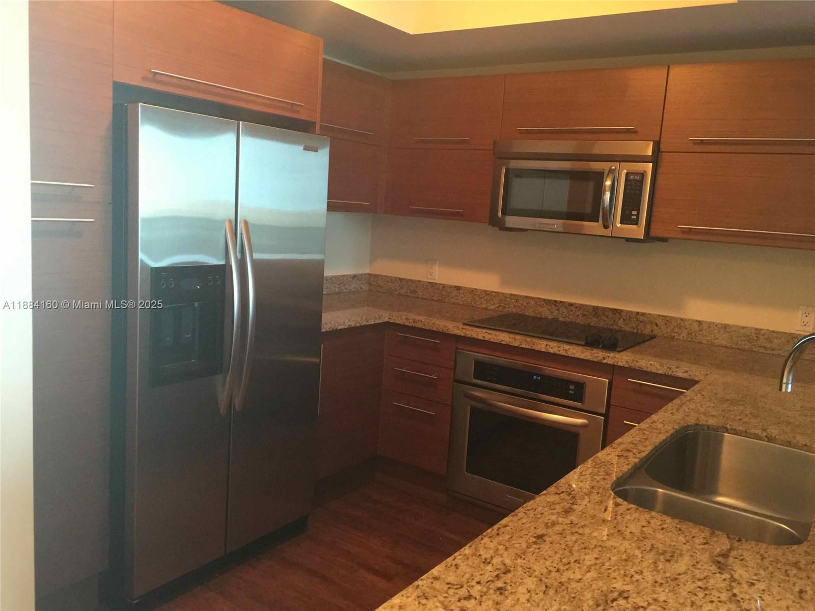 2641 North Flamingo Road, Unit 1705N Sunrise, FL 33323 - Photo 6 of 56 a kitchen with stainless steel appliances granite countertop a refrigerator and a microwave