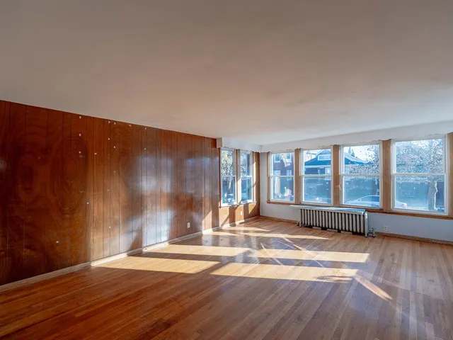 a view of an empty room with wooden floor and windows
