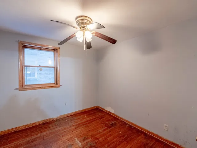a view of an empty room with window and chandelier fan
