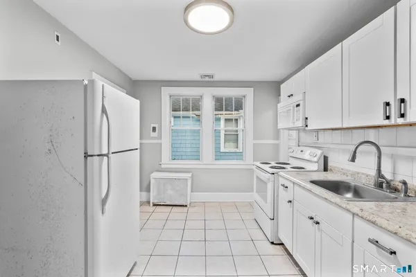 a kitchen with stainless steel appliances granite countertop a refrigerator sink and white cabinets