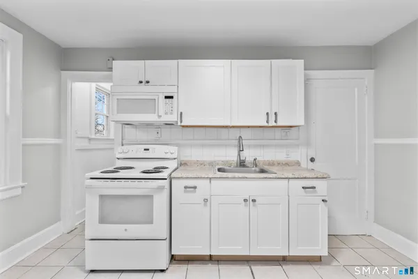 a kitchen with granite countertop white cabinets and white appliances