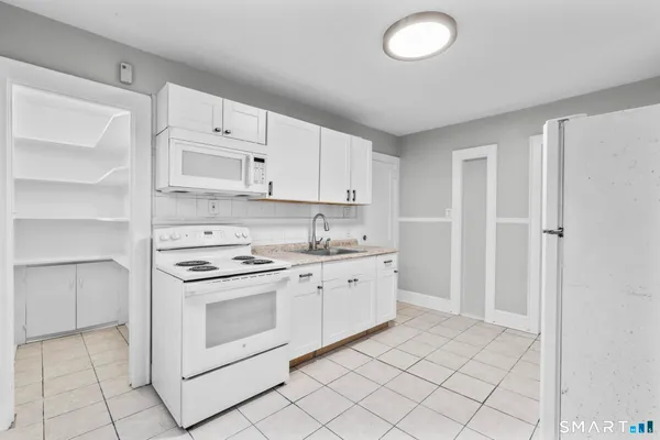 a kitchen with white cabinets and white appliances