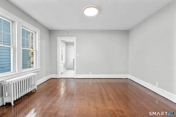 a view of an empty room with wooden floor and a window