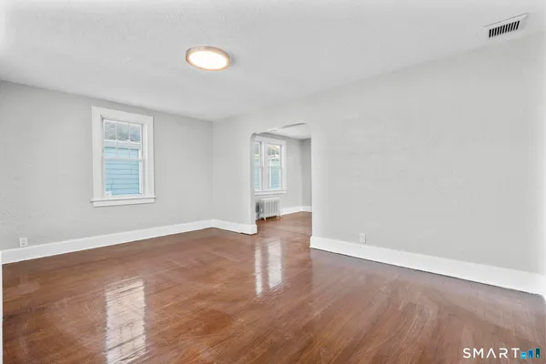 an empty room with wooden floor and windows