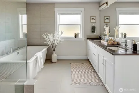 a bathroom with a double vanity sink a mirror and a bathtub