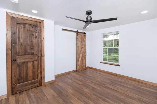a view of empty room with wooden floor and fan