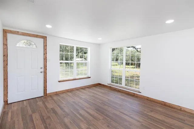 an empty room with wooden floor and windows
