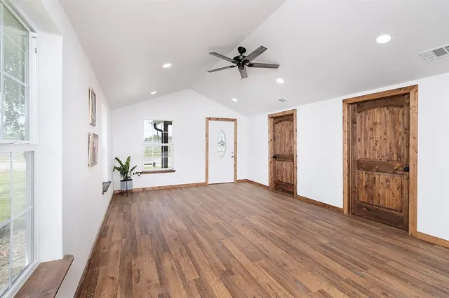 a view of an empty room with wooden floor and a window