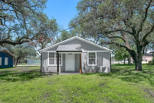 a view of a yard in front of a house with large windows
