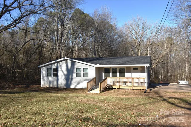a front view of house with yard and trees in the background
