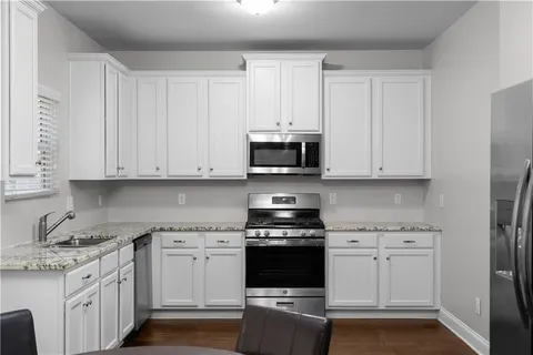 a kitchen with granite countertop white cabinets and stainless steel appliances