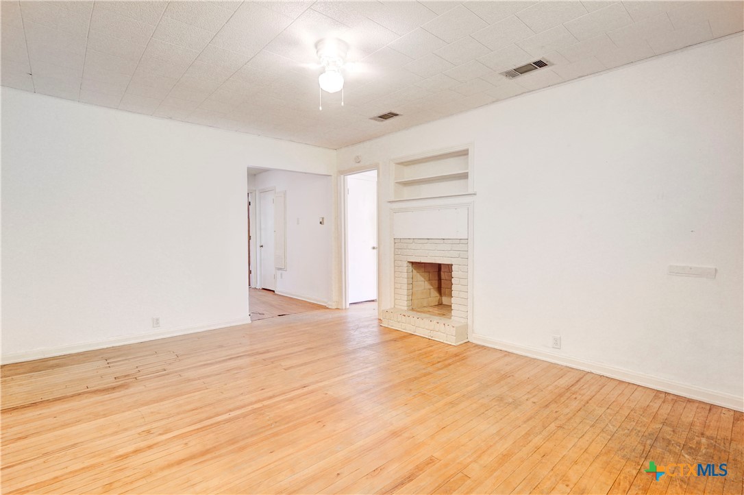 1415 North 7th Street Temple, TX 76501 - Photo 2 of 14 a view of empty room with wooden floor and fireplace