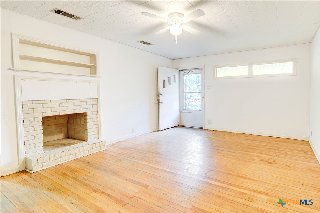 1415 North 7th Street Temple, TX 76501 - Photo 3 of 14 a view of empty room with wooden floor and fireplace