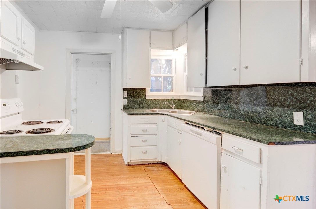 1415 North 7th Street Temple, TX 76501 - Photo 4 of 14 a kitchen with granite countertop white cabinets and white appliances