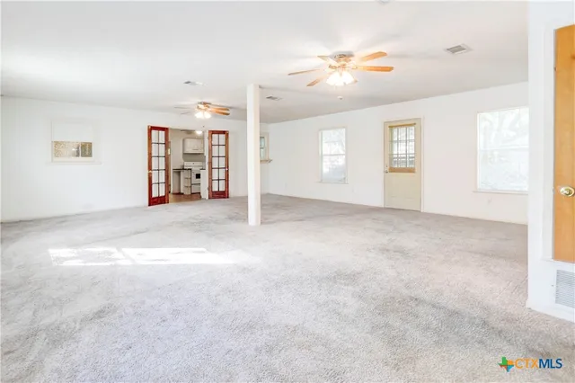 an empty room with windows and chandelier fan