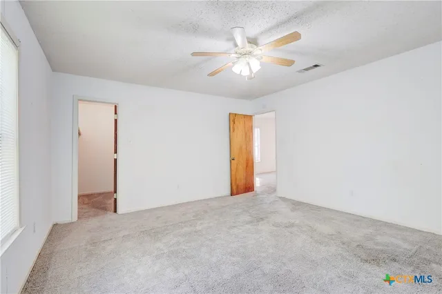 an empty room with a ceiling fan and a window