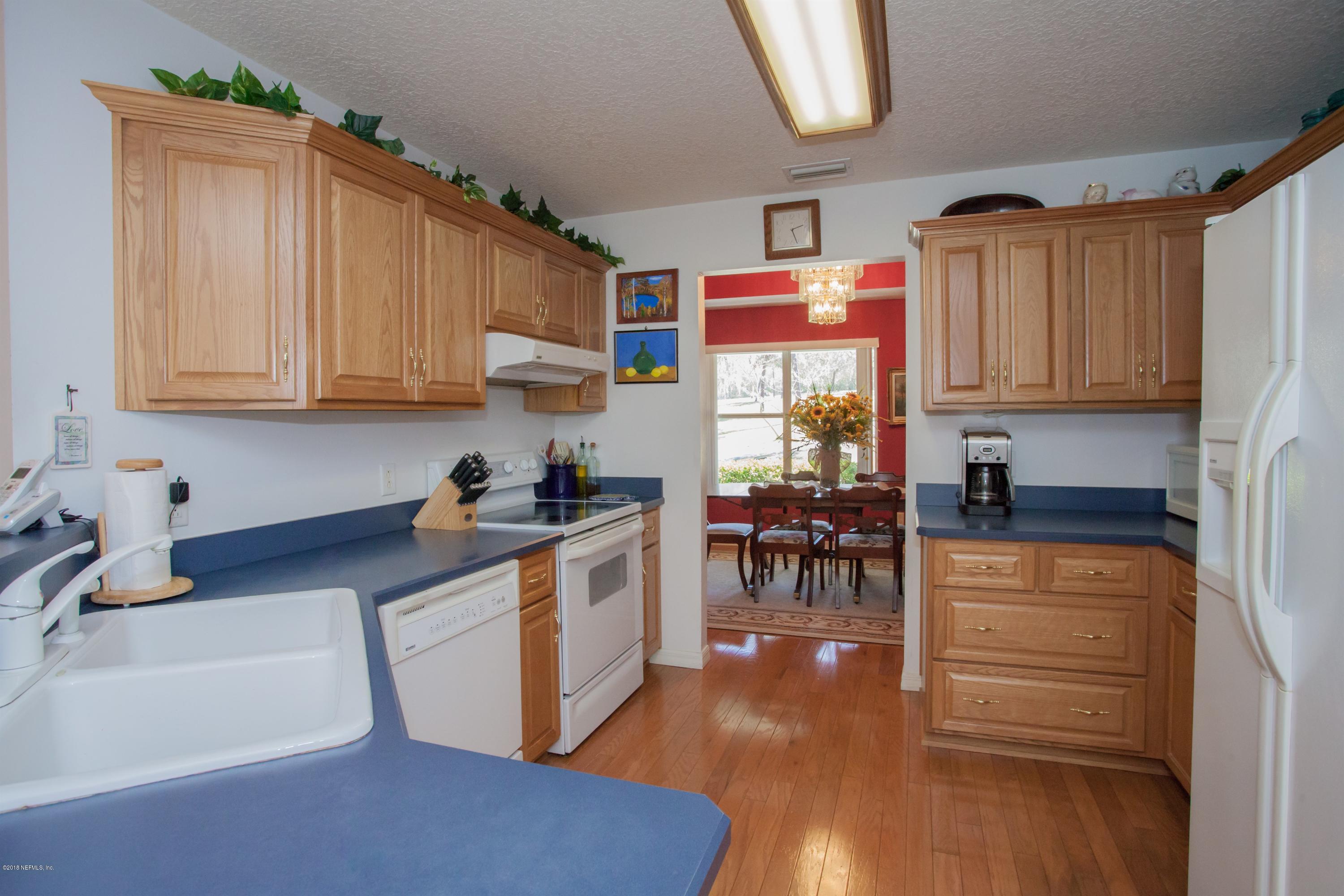 7986 National Forest Road Palatka, FL 32177 - Photo 11 of 31 a kitchen with stainless steel appliances granite countertop a stove top oven a sink a dining table and chairs with wooden floor