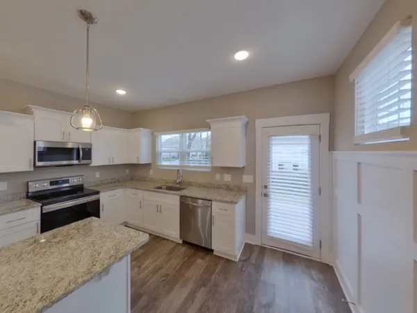 a kitchen with stainless steel appliances granite countertop hardwood a sink a stove a refrigerator and white cabinets