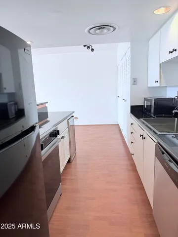 a kitchen with granite countertop a sink a stove top oven and refrigerator