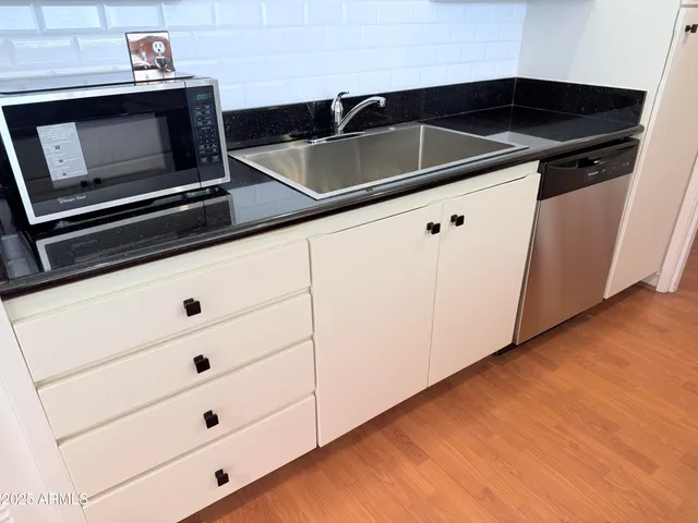 a kitchen with granite countertop white cabinets and black appliances